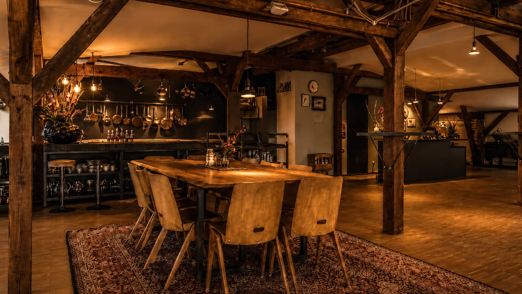 Long wooden table in front of an open kitchen in the loft